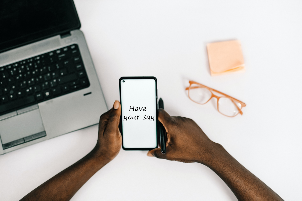 Image of a person holding a phone which has the text 'Have your say' written on it.