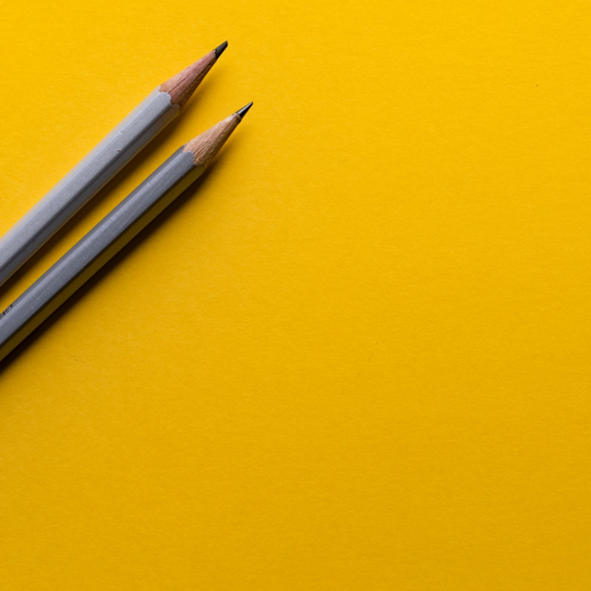 Two pencils against a yellow background.